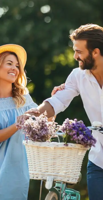 beautiful couple walking alongside bike with basket of flowers