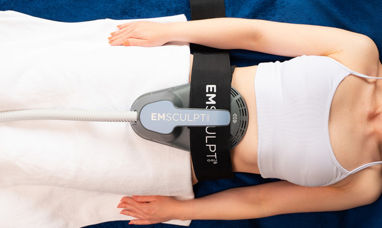 woman using EMSculpt NEO machine on abdomen